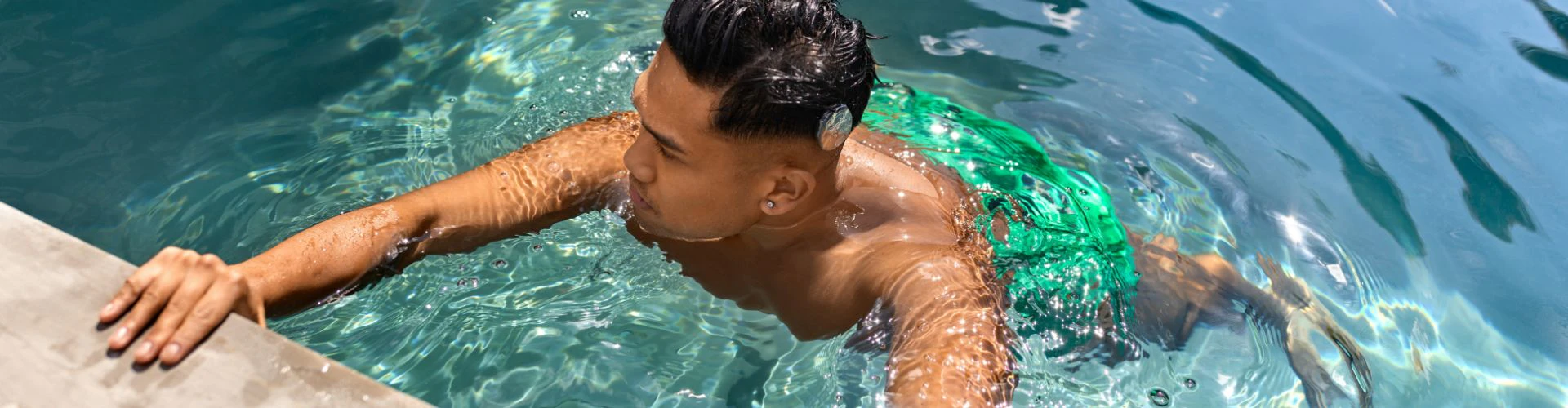 Човек във вода, хванал се за ръба на басейн. Мъжът носи RONDO 3 с поставен WaterWear