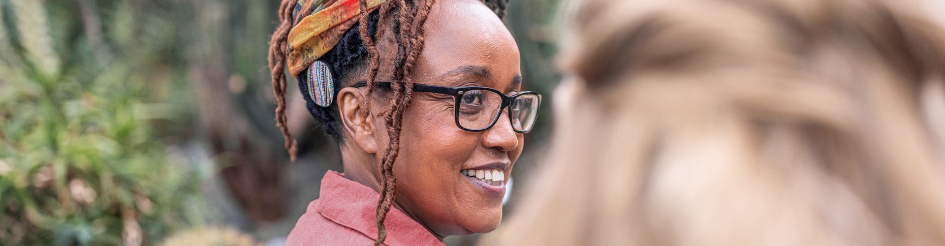 RONDO 3 user with glasses smiles as she listens to the nature sounds around her.