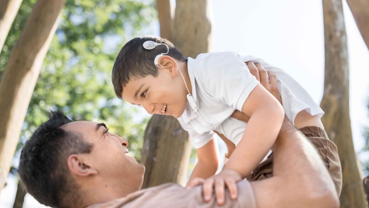 child playing with his father while his SONNET 3s’ flexible earhooks hold his audio processors securely in place