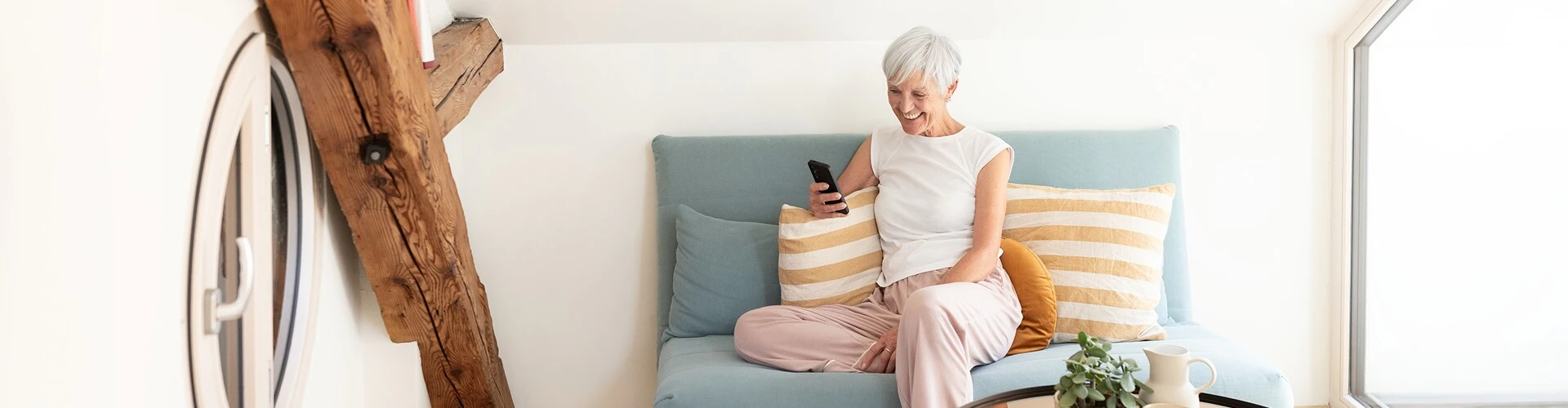 Older cochlear implant user streaming sound to her CI while video chatting on her phone.