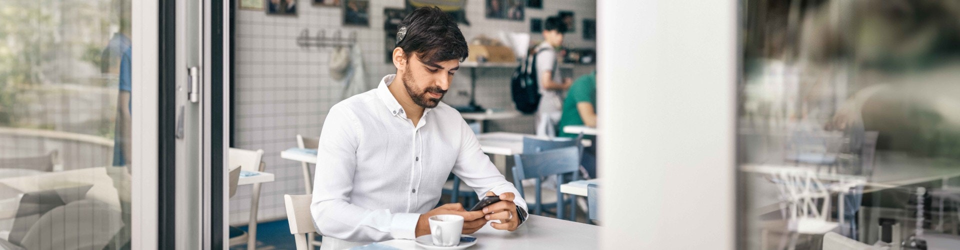 Ein SONNET 3 Nutzer in einem Cafe. Er überprüft seine Hörstatistiken in der AudioKey 3 App.