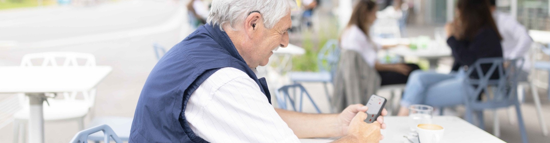 An elderly bimodal SONNET 3 and hearing aid user adjusting SONNET 3 settings with ease using the AudioKey 3 app