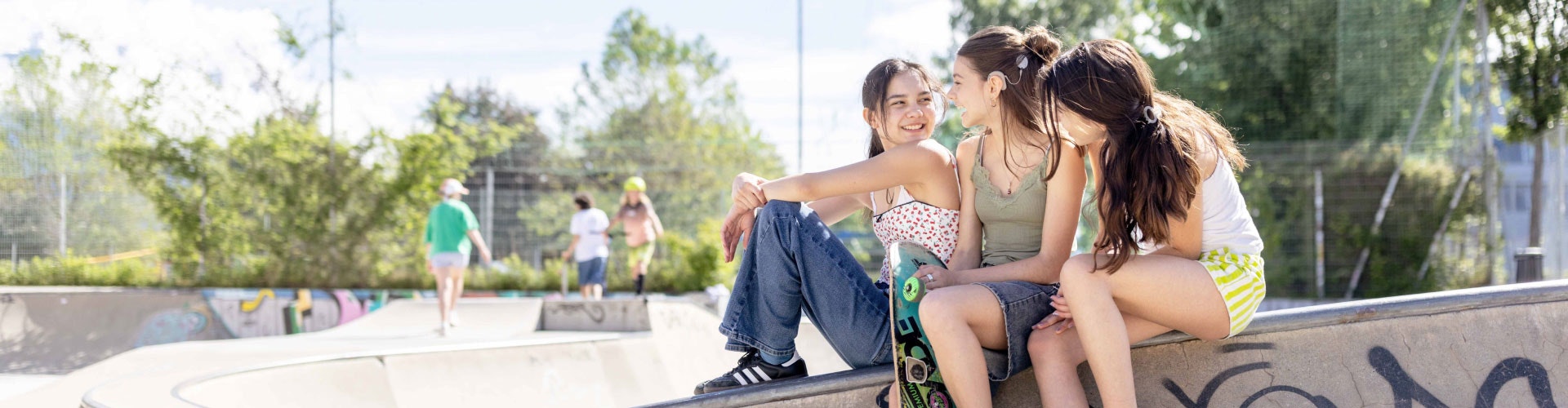 drie meisjes die in een skatepark zitten en een gesprek voeren