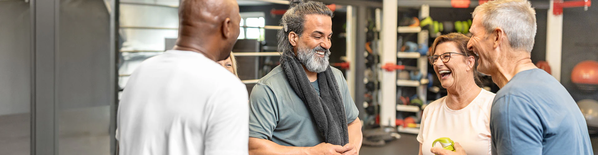 Group of adults talking in a gym setting. One man has a MED-El cochlear implant audio processor