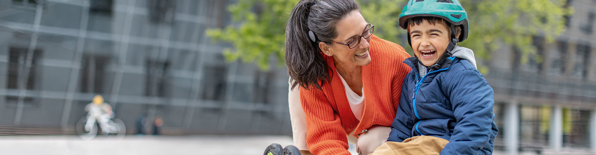 Woman with a cochlear implant audio processor assisting a young boy on a skateboard