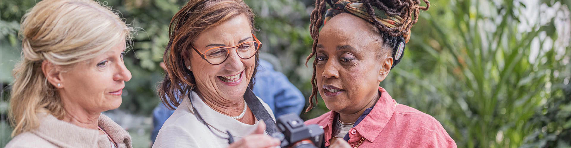 Group of women viewing a camera screen together. One has a cochlear implant audio processor