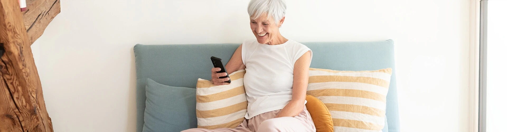 Person sitting on a sofa using a smartphone, wearing a SONNET 2 EAS audio processor.