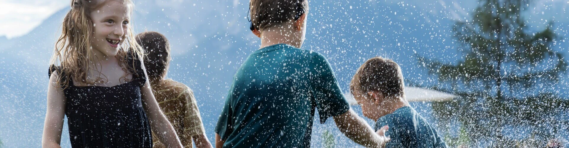 Children playing in outdoor sprinklers; the child in the middle wears a SONNET 2 EAS audio processor.